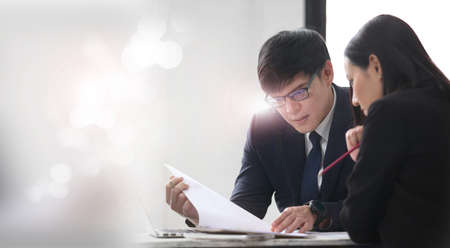 two young business people working and communicating while standing at the office with city building background.の写真素材