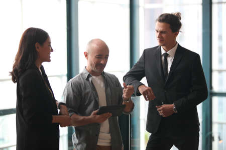 team young business people working and communicating while standing at the office with city building...