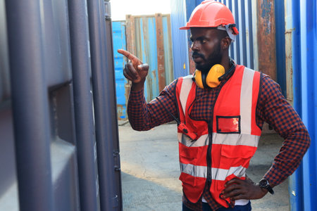 Close up of An African American handsome black engineer he is working in container box yard area of  logistics transportation import export or shipping industryの写真素材