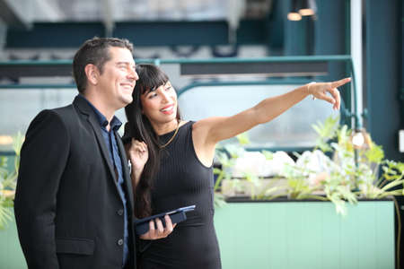 two young business people working and communicating while standing at the office with city building background.の写真素材