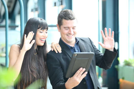 meeting online , two young business people working and communicating while standing at the office with city building background.の写真素材