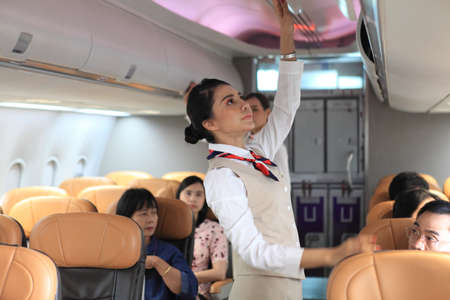 air  hostess service on plane , flight attendant checking and closing cabin compartment in airplaneの写真素材