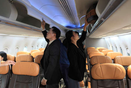 passenger in the airplane keeping bag in cabinの写真素材