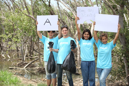 Happy volunteer working , volunteering, charity, cleaning, people and ecology concept - group of happy volunteers with garbage bags cleaning area in parkの写真素材