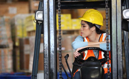 female driving forklift or Woman warehouse worker with forklift.worker in warehouse, Working at warehouse.International export business conceptの写真素材