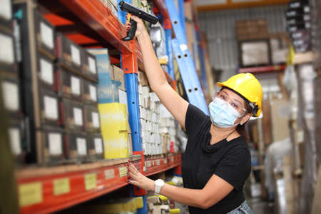worker in warehouse,  using bar code scanner to scanning box and analyze newly arrived goods.  Working at warehouse.International export business conceptの写真素材