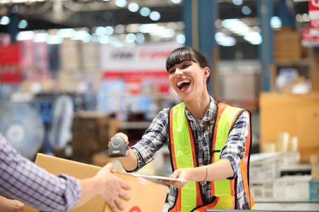 Portrait of female warehouse , she happy and  working at The Warehouse. Storehouse area, Shipment.  warehouse worker unloading pallet goods in warehouseの写真素材