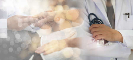 Medicine doctor with stethoscope in hand and Patients come to the hospital background.Healthcare people group. Professional doctor working in hospital office or clinic with other doctorsの写真素材