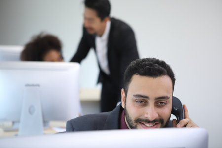 Happy attractive business people. Call center worker accompanied by team. Smiling customer support operator at work. Young employee working with a headset. Successful business professionals.の写真素材
