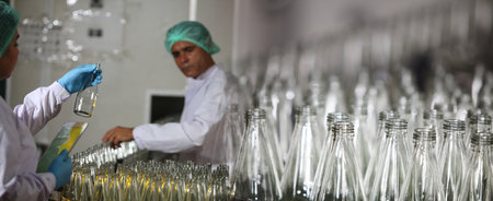 Conveyor belt, industrial production line, juice in bottles on beverage plant , selective focus.Factory worker inspecting production line of drink production in factory , Concept of food industryの写真素材