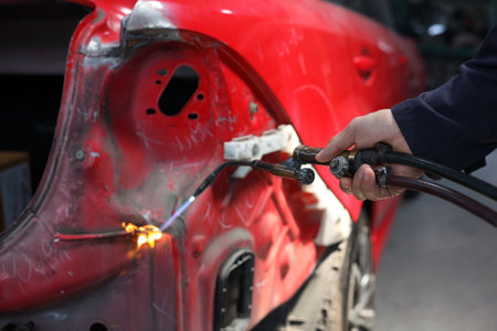 Auto mechanic working in garage. Repair service. Worker mechanics in uniform are working in auto service with lifted vehicle. Car repair maintenance.の写真素材