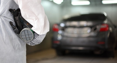 auto mechanic worker painting ,  automobile repairman painter in protective workwear and respirator painting car body in paint chamberの写真素材