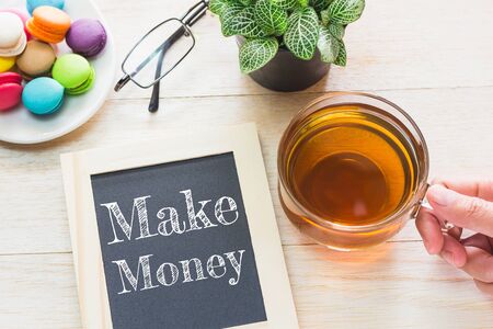 Concept Make Money message on wood boards. Macaroons and glass Tea on table. Vintage tone.の写真素材
