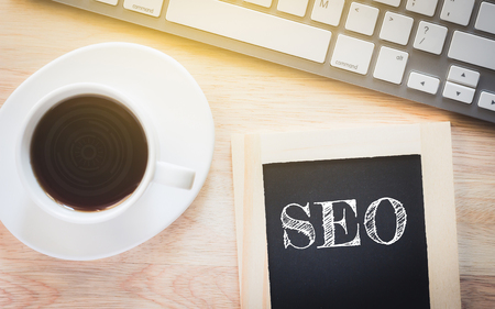 Concept SEO message on wood boards. A keyboard and a glass coffee table.Vintage tone.の写真素材