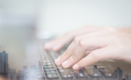 Double exposure of business women hand working on keyboard computer on wooden desk as concept