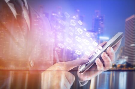 Double exposure of city and businessman standing touch the screen on smartphone. concept working online, by emailの写真素材