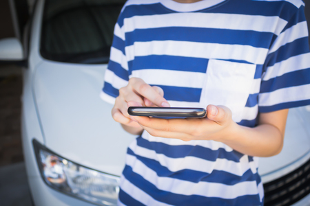 woman hand holding and using mobile on car background, concept calling mechanic service from repair shopの写真素材