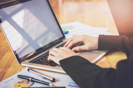 soft focus of woman hand working laptop on wooden desk in office in morning light. vintage effectの写真素材