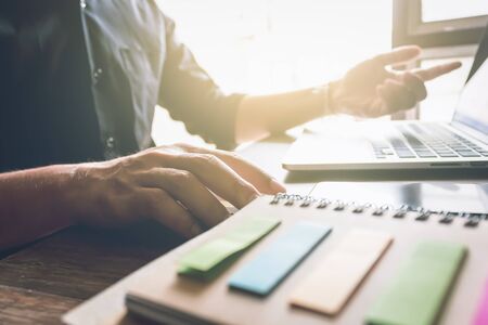 businessman hand working laptop on wooden desk in office in morning light. vintage effectの写真素材