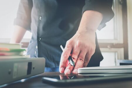 businessman hand working laptop on wooden desk in office in morning light. vintage effectの写真素材