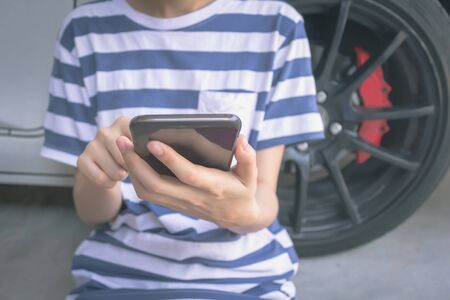 woman hand holding and using mobile on car background, concept calling mechanic service from repair shop. vintage effectの写真素材