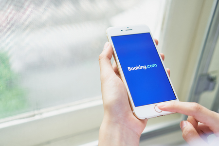 Bangkok, Thailand - August 23, 2017 : Women hold a phone with a screen Booking.com logo on iPhone 6. Online travel agency based that offers accommodation its website and mobileのeditorial素材