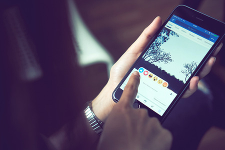 Bangkok, Thailand - August 24, 2017 : hand is pressing the Facebook screen on smartphone ,Social media are using for information sharing and networking.のeditorial素材