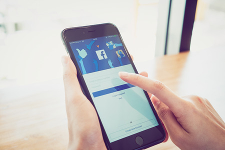 Bangkok, Thailand - January 2, 2017 : hand is pressing the Facebook screen on apple iphone6 ,Social media are using for information sharing and networking.のeditorial素材