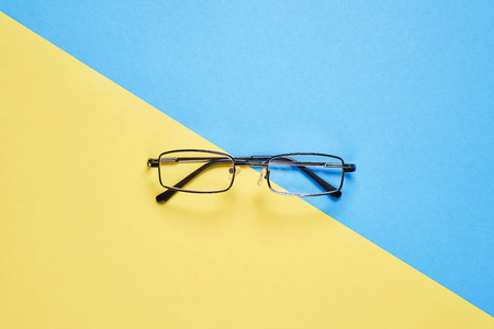 Eyewear placed on a pastel yellow and blue background divides the halves.の写真素材