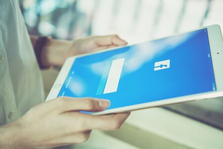 Bangkok, Thailand - January 15, 2018 : hand is pressing the Facebook screen on the tablet, Social media are using for information sharing and networking.のeditorial素材