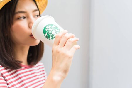 Bangkok, Thailand - January 30, 2018 : Woman drinking Starbucks coffee on the home, Starbucks brand is one of the leaders in coffee service worldwide.のeditorial素材