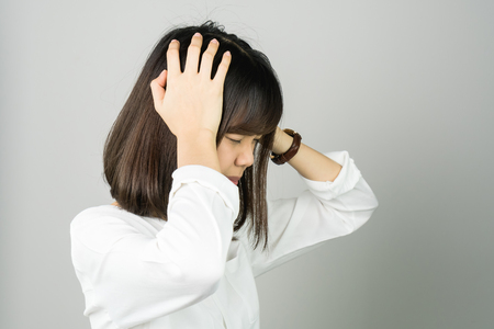 Woman in a white dress is touching head to show her headache. Causes may be caused by stress or migraine. Or because too much work. The concept of stress from hard work is bad for health.の写真素材