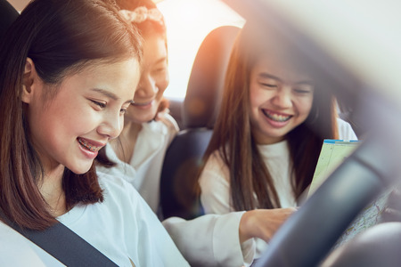 Vacation time and travel, three beautiful young women cheerful travels together for a relaxing holiday. And the laughter in the car. Finding directions by map.の写真素材
