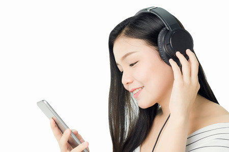 Asian Women are listening to music from black headphones. In a comfortable and good mood, on a white background gives a soft light.の写真素材