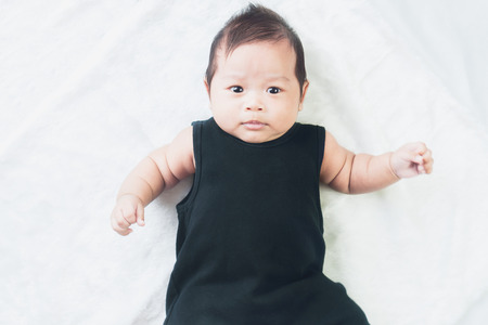 Cute little baby lies on a black cloth, Looking camera. on white background.