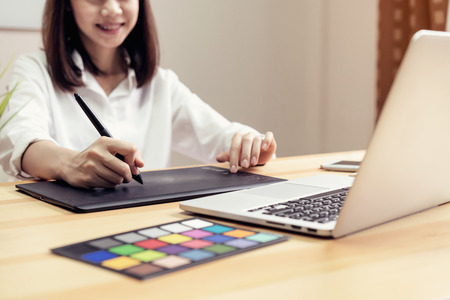Businesswoman in office in casual shirt. Use computer for graphic designer and choose a color sample...