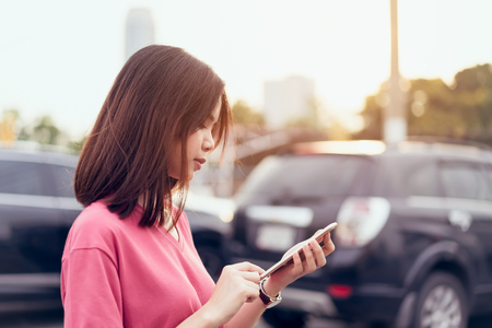 Woman using smartphone for the application on car blur background. Concepts for digital technology in everyday Life.の写真素材