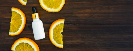 White vitamin c bottle and oil made from orange fruit extract, mockup of beauty product brand. Top view on the wood background.の写真素材