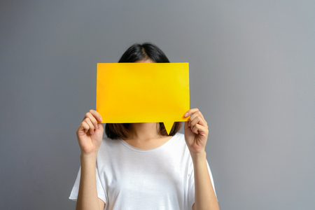Young woman holding a blank poster for text on a white background.の写真素材
