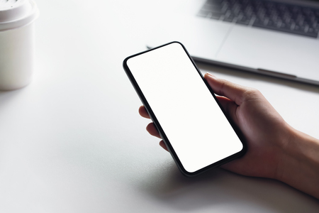 Woman holding smartphone mockup of blank screen on the table.の写真素材