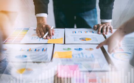 double exposure of business people meeting team working on wooden desk and hand man pointing to financial documents in office. successful meeting workplace strategy.の写真素材
