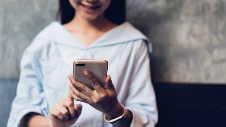Smiling of asian woman using smartphone texting on the cafe. copy space for ads.の写真素材