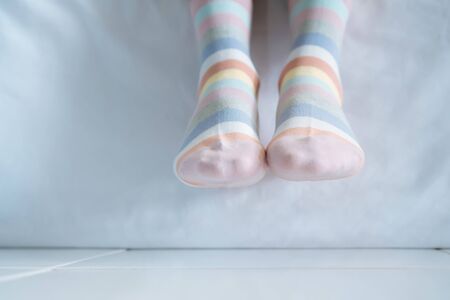 Women's legs in socks colors alternating, side stand on white fabric floor.の写真素材