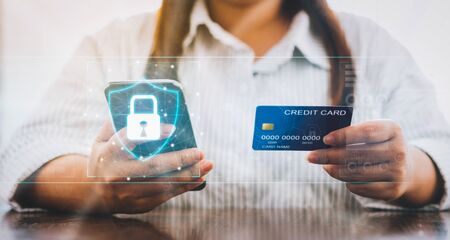 Woman holding smartphone and credit card with padlock icon on digital display cyber security internet and networking, Concepts online shopping for protection.の写真素材