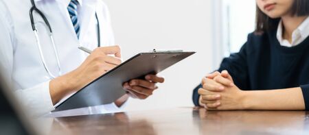 Close up of doctor and patient sitting hands at the table and talking about the patient's condition. writing a prescription, Healthcare and medical.の写真素材