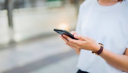 Woman hand using black smartphone. The concept of using the phone is essential in everyday life.の写真素材