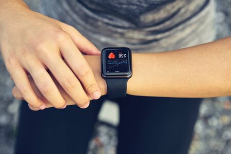 Young woman checking the sports watch measuring heart rate and performance after running.の写真素材