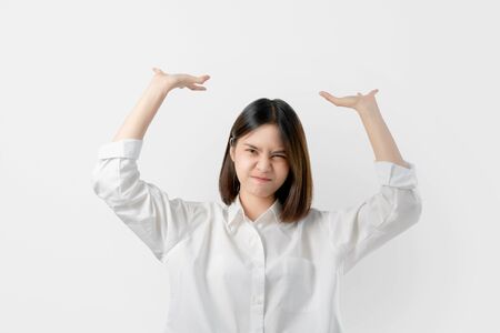 Young Asian woman in white casual clothes attempt to hold something heavy from above.の写真素材