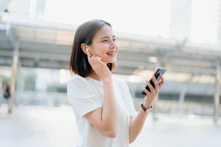 Women are listening to music from white headphones. And using hands touch to use various functions, happy mood.の写真素材