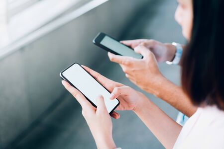 woman and man  holding a smartphone, mock up of blank screen. using cell phone on lifestyle. Technology for communication concept.の写真素材